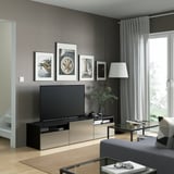 Modern living room with gray walls, tv on console, glass table, lamp, framed pictures.