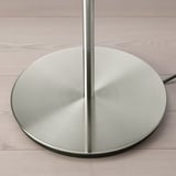 Modern metallic lamp base on wooden floor; sleek, reflective finish; sturdy design.
