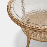 Wicker side table with clear, patterned glass top, showcasing quality craftsmanship and stylish design.