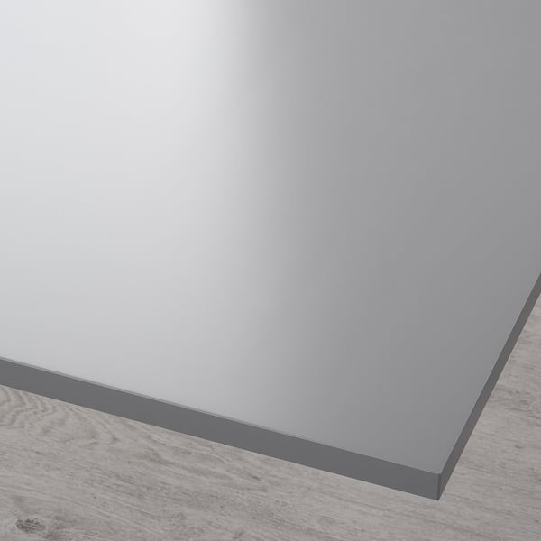 Close-up of a smooth, grey tabletop with a sleek, glossy finish and a peripherally visible wooden floor.