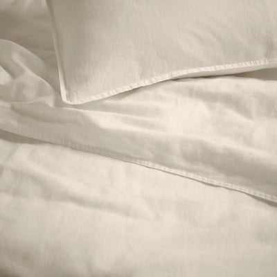 A folded beige bed linen set, consisting of a duvet cover and pillowcases, neatly stacked, with an envelope closure design.