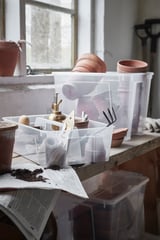 Plastic SAMLA boxes with gardening tools on shelf near window.