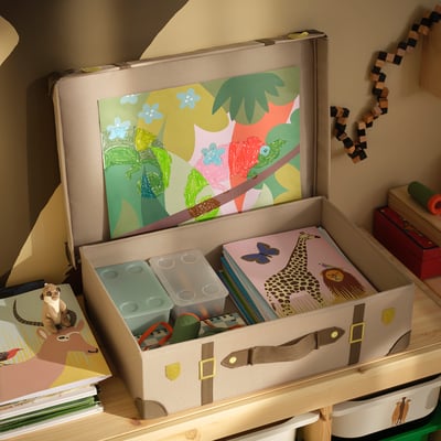 Beige travel trunk with brown straps, yellow buckles, and colorful stickers. Perfect for storage and playful adventures.