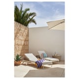 Modern outdoor lounging area with white SEGERÖN recliners, striped towel, side table, and palm tree.
