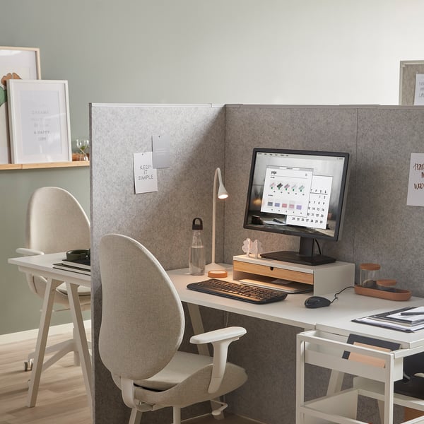Modern office setup with white desk, gray chair, monitor, keyboard, mouse, lamp & water bottle. Room divider panel rear center.
