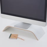 A monitor stand with a laptop, holding a monitor at an ergonomic height. Below it, a notepad and pencil show accessible storage.