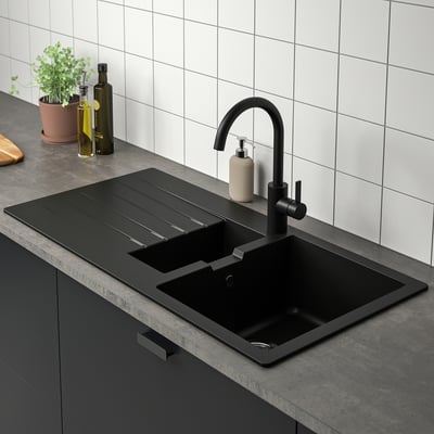 Modern kitchen sink with black faucet and reversible drainboard.