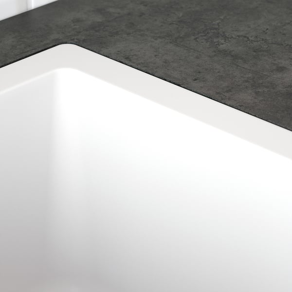 Sleek white sink with smooth edges, minimalist design, and clean lines, set against a textured grey countertop.