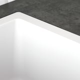 Sleek white sink with smooth edges, minimalist design, and clean lines, set against a textured grey countertop.
