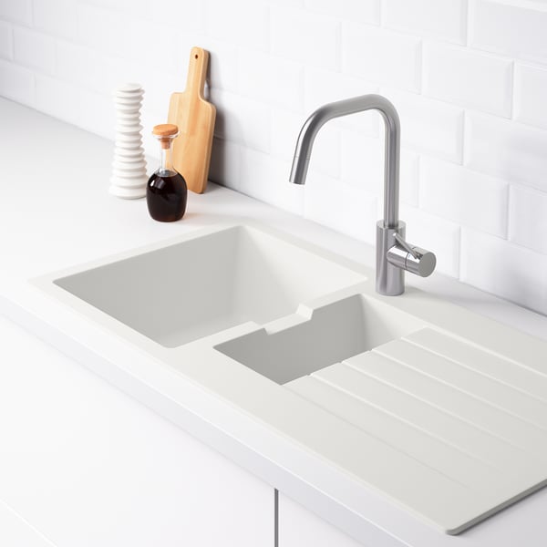 Clean, modern kitchen sink with a sloping drainboard on the right, silver faucet, and backsplash.