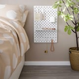 SKÅDIS pegboard with accessories near bed and plant.