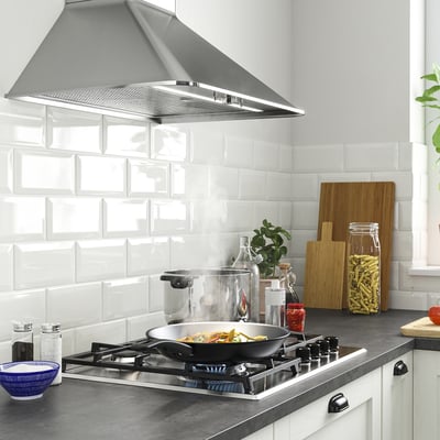 Modern kitchen with SKÅLAN gas hob, hood, white backsplash, and kitchen items.