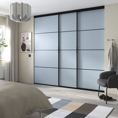 Modern bedroom with large gray sliding closet doors, a gray rug, and a bed with gray and beige bedding.