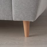Close-up of a stylish sofa leg with light wood texture, part of a modern, comfortable piece of furniture.