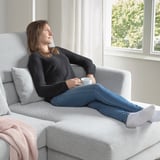 Woman relaxes on adjustable sofa with coffee cup.