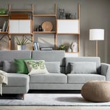 Gray l-shaped sofa with toss pillows and wooden legs in stylish living room.