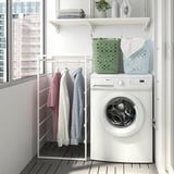 Modern laundry room with washing machine, shirts on rack, and colorful laundry baskets.