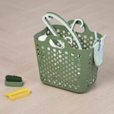 Green perforated laundry basket with white handles, containing cleaning brushes and tools, ideal for organizing and transporting clothes.