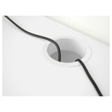 White desk with black cord neatly fed through circular cable hole for organized setup.