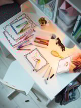 White SMÅGÖRA kids desk with toys & supplies, rounded edges.