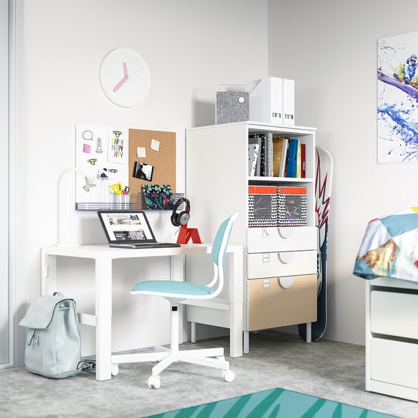 Modern teen bedroom with white desk, blue chair, laptop, bookshelf, and colorful wall art.
