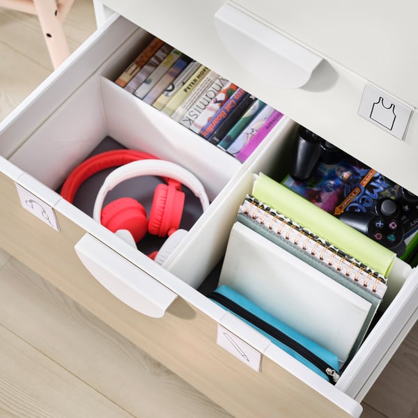 White SMÅSTAD drawers with red headphones, notebooks, and books organized inside.