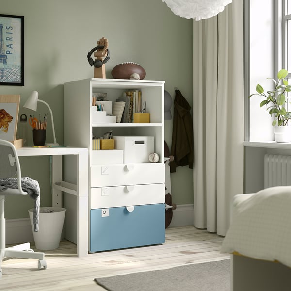 Small, cozy room with white SMÅSTAD storage, football, and art. Light green walls, desk, lamp, and window with sheer curtains.