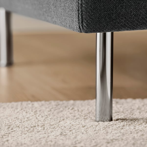 Modern, sleek sofa with polished metal legs, textured grey upholstery, on soft carpet.