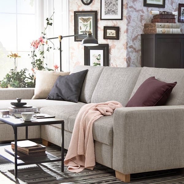 Modern living room with light gray SÖRVALLEN sofa, decorated with cushions and a throw, near a small table with a cup of tea and a book.