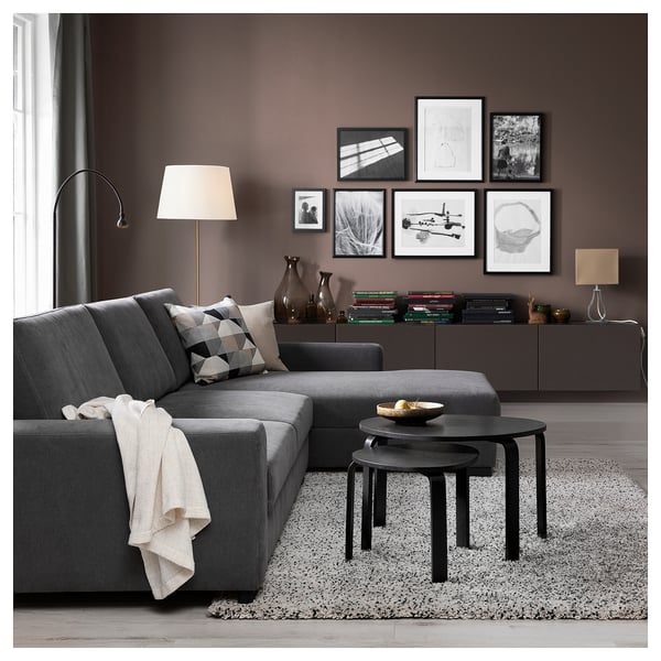 Modern living room with gray SÖRVALLEN sectional sofa, black nesting tables, patterned rug, and wall art.