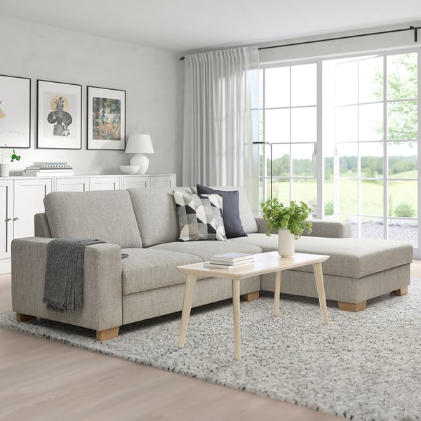 Gray SÖRVALLEN sofa with wood accents, pillows, and coffee table. Bright window creates a warm living space.