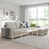 Gray SÖRVALLEN sofa with wood accents, pillows, and coffee table. Bright window creates a warm living space.