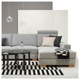 Modern living room with gray SÖRVALLEN sofa, black-white striped rug, black coffee table, hanging lamps, and accessories on sofa.