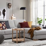 Modern living room with grey SÖRVALLEN sofa, colorful pillows, wooden side table, black lamp, and plants.