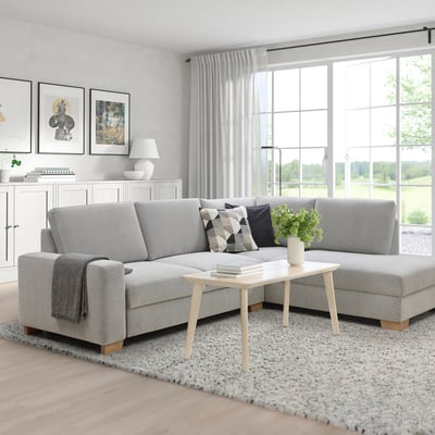 Modern living room with SÖRVALLEN gray sofa, large windows. Light wood coffee table, white curtains. Minimalist design.