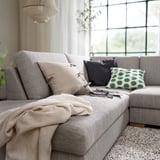 Cozy living room with gray SÖRVALLEN sofa, large window, curtains, pillows, blanket, and plant.