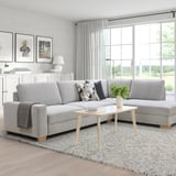Modern minimalist living room with large l-shaped gray sofa, side table, neutral decor.