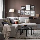 Modern living room with SÖRVALLEN grey sofa, colorful pillows, dark coffee tables, and wall art.