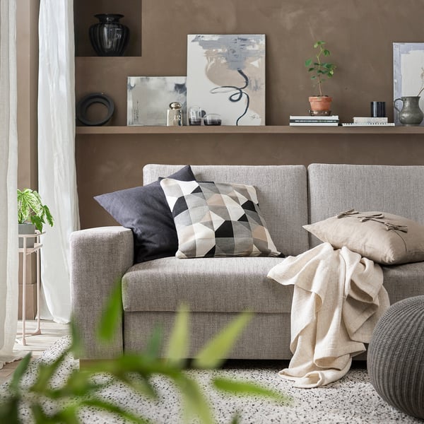 Modern living room with gray SÖRVALLEN sofa, geometric cushions, art, and plants.