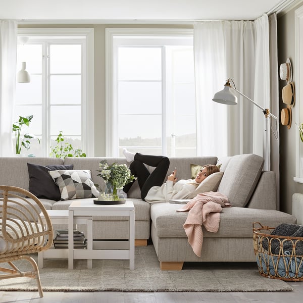 Living room with SÖRVALLEN sofa, person relaxing, natural light, floor lamp, wall hats.