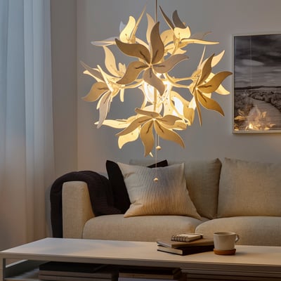 Unique floral pendant light, modern living room with beige sofa, coffee table, and books. Light numerous leaf-like shades, casting warm illumination.