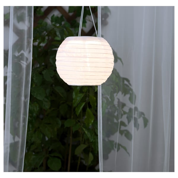 Hanging solar lantern glows softly, illuminating outdoor space. Made from recycled materials, it charges during the day and lights up at night.