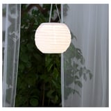 Hanging solar lantern glows softly, illuminating outdoor space. Made from recycled materials, it charges during the day and lights up at night.