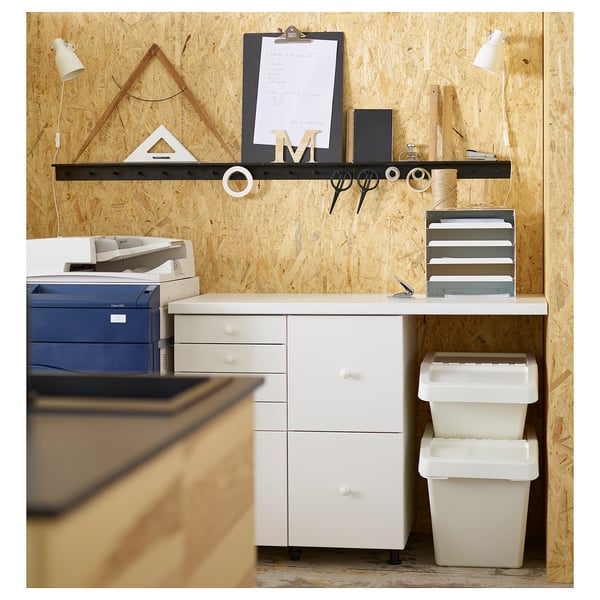 Office desk setup with white SORTERA storage bins, a blue printer, and a wall with shelves and tools.