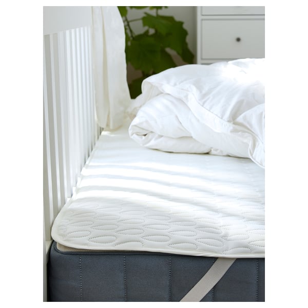 White mattress protector on bed with wadding, waterproof layer, elastic straps for fit.
