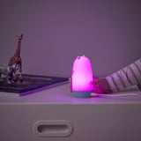 Childs hand with pink otter night light. Glows, changes colors, near toys & books.