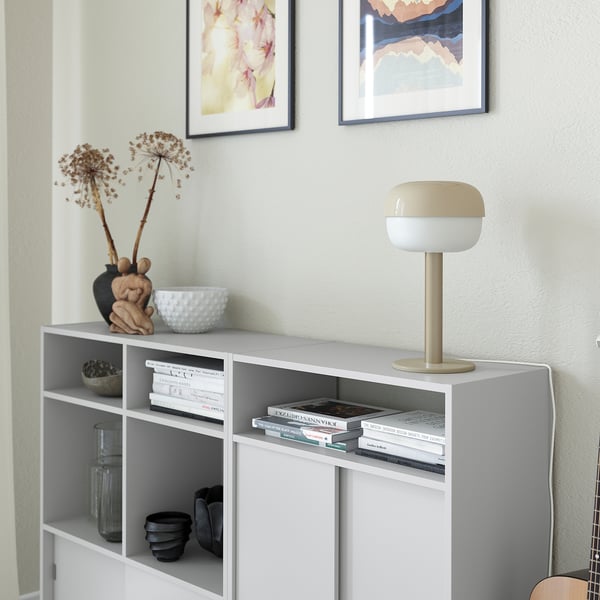 White bookshelf with lamp, books, and decor.
