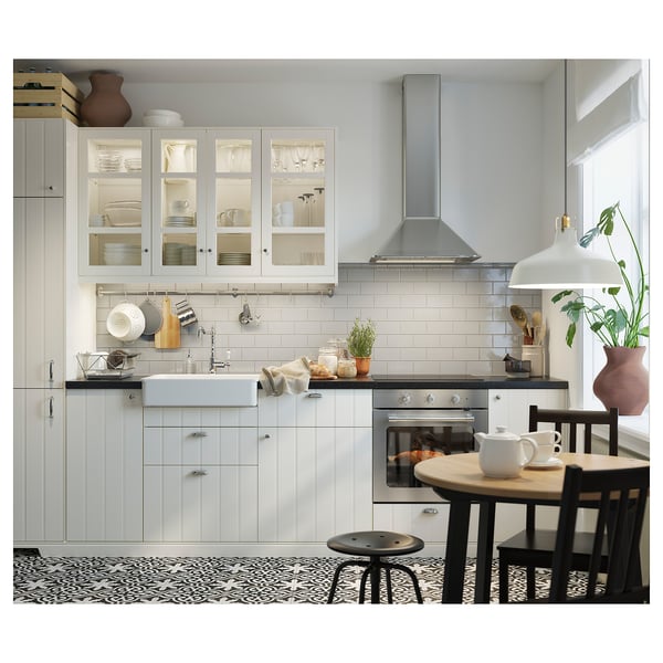Modern kitchen with white cabinets, black countertops, stainless steel appliances, and a black chair near a wooden table.