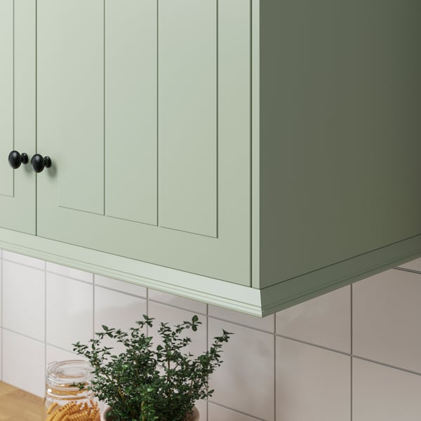 Green cabinets, black knobs, white tiles, under-cabinet lighting.
