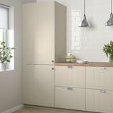 Beige STENSUND kitchen cabinet with grooved panels beside window.